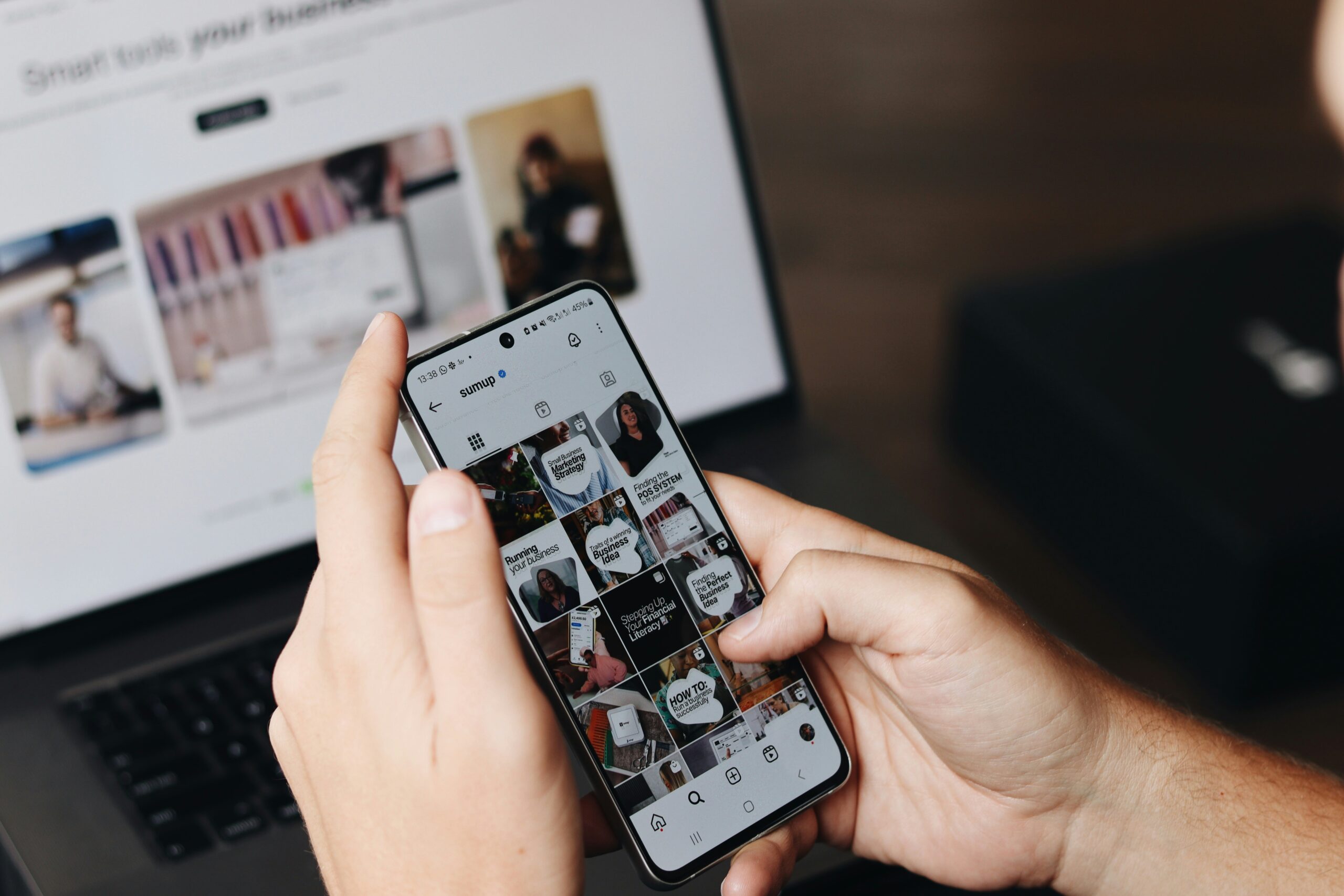 a person holding a A person holding a cell phone in front of a laptop
